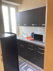 een keuken met zwarte kasten, een magnetron en een wastafel bij Appartement « Athènes » à Avignon in Avignon