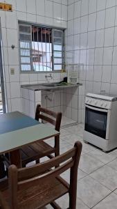 - une cuisine avec une cuisinière, une table et un banc dans l'établissement Casa Caraguatatuba Nelson, à Caraguatatuba