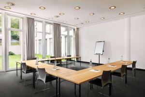 a meeting room with wooden tables and chairs at Vienna House Easy by Wyndham Trier in Trier