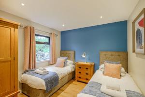 two beds in a bedroom with a blue wall at Birch Lodge 23 with Hot Tub in Newton Stewart
