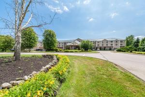 a road in front of a building with a tree and flowers at Bellissimo Hotel, Trademark by Wyndham Near Foxwoods Casino in North Stonington