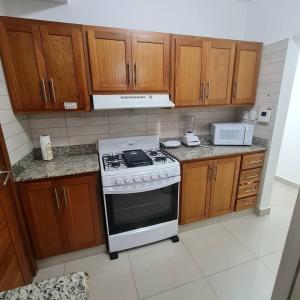 a kitchen with a white stove and wooden cabinets at Apartamento completo en Bella vista 1 o 2 dormitorios in Santo Domingo