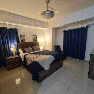 Schlafzimmer mit einem großen Bett und blauen Vorhängen in der Unterkunft Apartamento completo en Bella vista 1 o 2 dormitorios in Santo Domingo