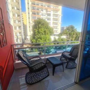 3 Stühle und ein Tisch auf einem Balkon mit Aussicht in der Unterkunft Apartamento completo en Bella vista 1 o 2 dormitorios in Santo Domingo