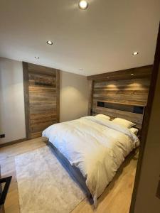 ein Schlafzimmer mit einem großen Bett mit einem hölzernen Kopfteil in der Unterkunft Appartement centre megeve in Megève