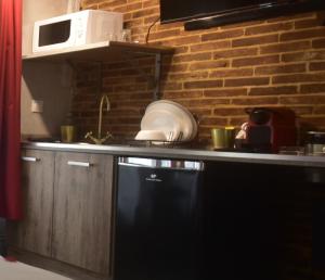 uma cozinha com uma máquina de lavar louça preta e uma parede de tijolos em Appartement jacuzzi privatif : Urban Love em Verneuil d’Avre et d’Iton