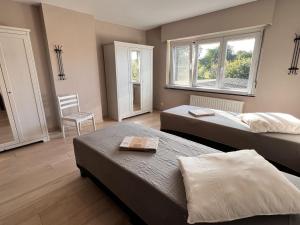 sypialnia z 2 łóżkami i krzesłem oraz 2 oknami w obiekcie Beautiful house with 4 bedrooms in Hees w mieście Bilzen