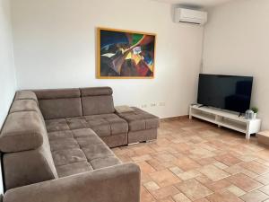 uma sala de estar com um sofá e uma televisão de ecrã plano em Olea Mar apartma em Pobegi