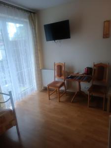 sala de estar con mesa, sillas y TV en Villa Aura, en Ciechocinek