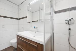 a white bathroom with a sink and a shower at EXQUIS Kunstvolles Luxusapartment I Designmöbel I Balkon I Homeoffice I Parken I Netflix in Böblingen
