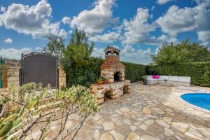a backyard with a brick fireplace next to a swimming pool at Holiday house Marinela with Private Pool and Fenced Garden in Radetići
