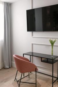a chair and a table with a television on a wall at Hotel Boutique Casa Romana Villa in Seville