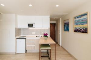 a kitchen with white cabinets and a table with flowers on it at The White Apartments in San Antonio