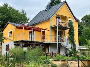 a yellow house with a black roof at Kleine-Radoase Ferienwohnung mit Super- Aussicht in Weilburg