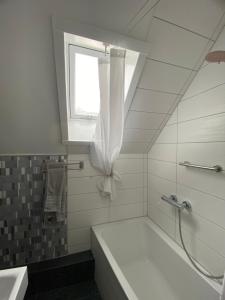 a white bathroom with a tub and a window at Kleine-Radoase Ferienwohnung mit Super- Aussicht in Weilburg