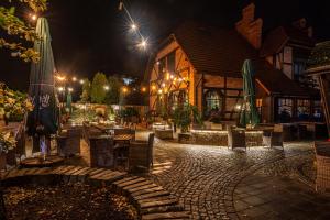 a restaurant with tables and chairs and umbrellas at night at Hotel Galicja Wellness & SPA in Oświęcim