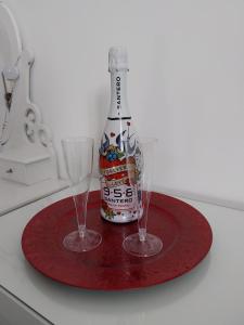 a bottle of beer and two glasses on a red plate at Suite al Borgo in Aversa