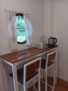 kuchnia ze stołem z 2 krzesłami i oknem w obiekcie Baankanoonpai(บ้านขนุนปาย)​ w mieście Pai