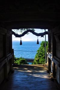 a view of the ocean from a tunnel with bells at 海に恋する泊まれる喫茶店 ポパイ in Iyo