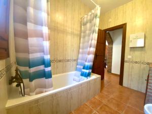 ein Badezimmer mit einer Badewanne und einem Duschvorhang in der Unterkunft Casa Las Herriza By Solymar Holiday in Alcaucín