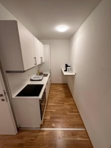 a small kitchen with white cabinets and a wooden floor at MUZETA11 - Modern Town Apartment with Balcony in Vienna