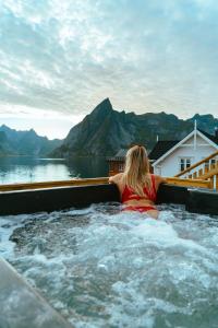 a woman sitting in a jacuzzi tub with a view at Reinefjorden Sjøhus in Reine