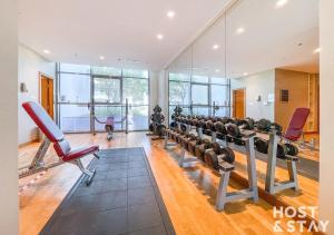 - une salle de sport avec des rames d'appareils d'exercice et des miroirs dans l'établissement Studio in Golf Vista, Damac Hills - Host & Stay, à Dubaï
