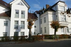 un gran edificio blanco con árboles delante de él en Schloss Hohenzollern Wohnungen Obergeschoss, en Ahlbeck