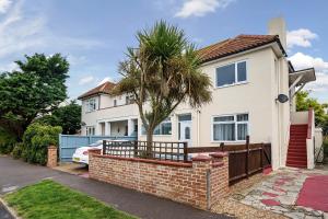 a white house with a palm tree in front of it at Sandy Feet Retreat in South Hayling