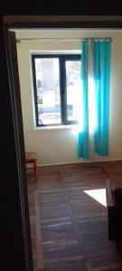 チャルトゥボにあるSergo's Appartmentの青いカーテン付きの窓が備わるウッドフロアの客室です。