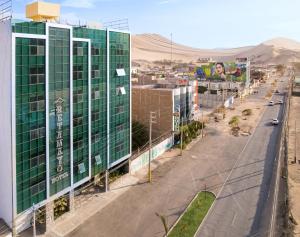 een stadsstraat met een hoog groen gebouw en een weg bij Hotel Retamayo in Ica