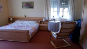 a bedroom with a bed and a chair and a table at B&B De Boerderij in Berdorf