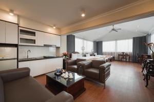 a living room with a couch and a table and a kitchen at Hanoi Little Town Hotel in Hanoi