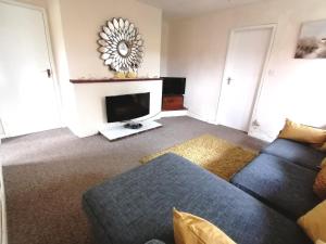 uma sala de estar com um sofá e uma televisão em Cartref Bach em Llanybyther