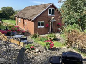a small brick house with a garden and flowers at Cartref Bach in Llanybyther