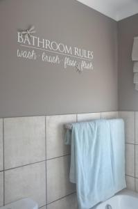 a bathroom with a bathroom rules sign on the wall at Estoril Villas 10 in Mossel Bay +14 photos