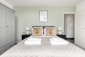a white bedroom with a large bed with two lamps at The Canary Wharf Collection in London