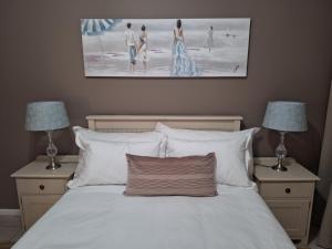 a bedroom with a bed with two lamps and a painting at Estoril Villas 10 in Mossel Bay