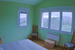 1 dormitorio con 2 sillas, 1 cama y 2 ventanas en Casa el Cerezo Rojo en El Rasillo