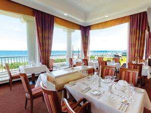 a restaurant with white tables and chairs and the ocean at Morada Strandhotel Ostseebad Kühlungsborn in Kühlungsborn