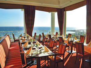 a restaurant with tables and chairs and the ocean at Morada Strandhotel Ostseebad Kühlungsborn in Kühlungsborn
