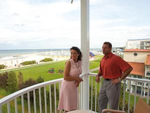 a man and a woman standing on a balcony overlooking the beach at Morada Strandhotel Ostseebad Kühlungsborn in Kühlungsborn