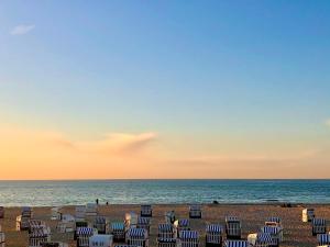a group of chairs on the beach at sunset at Morada Strandhotel Ostseebad Kühlungsborn in Kühlungsborn