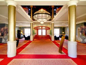 a large lobby with a chandelier and red carpet at Morada Strandhotel Ostseebad Kühlungsborn in Kühlungsborn