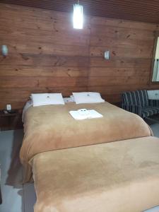 two beds in a room with wooden walls at Pousada da Chacara in Nova Petrópolis