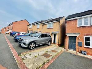 um carro estacionado num parque de estacionamento em frente às casas em New beautiful house in a perfect location em Newcastle under Lyme