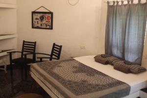 a bedroom with a bed with two chairs and a desk at MINT INSIDE GARDEN in Varkala