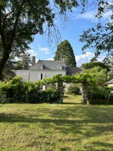 Corné的住宿－La Maillardière - Maison de campagne avec piscine，庭院中一座带拱门的老房子