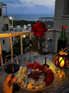 einen Teller mit Lebensmitteln auf einem Tisch mit Weingläsern in der Unterkunft Sea view apartment near the beach in Paphos City