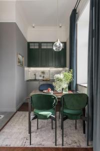 uma cozinha com armários verdes e uma mesa com cadeiras verdes em Вишукані апартаменти у історичному маєтку в парку em Kiev